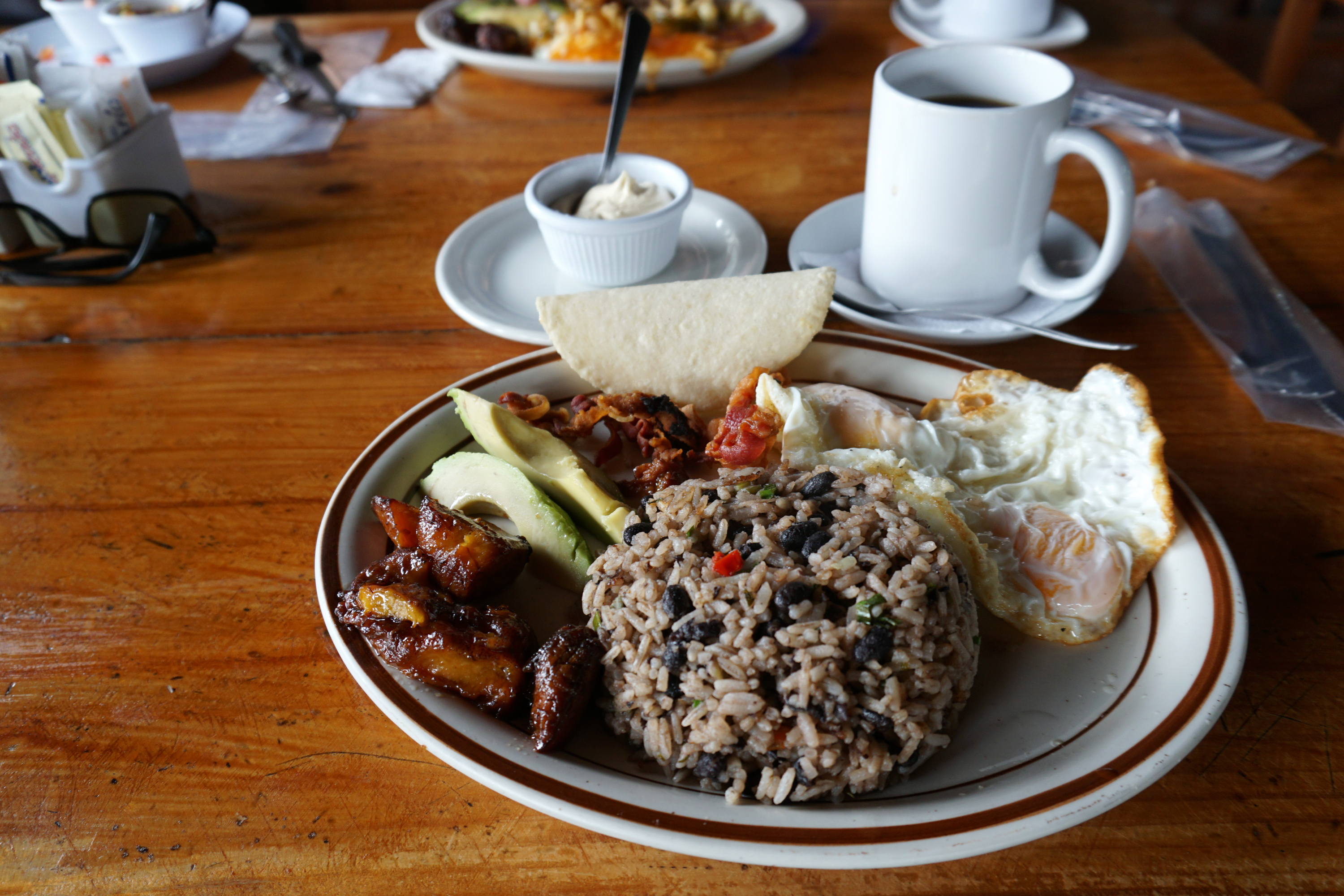 Traditional Tico breakfast — gallo pinto, fried eggs, sweet plantains, avocado, and farm coffee
